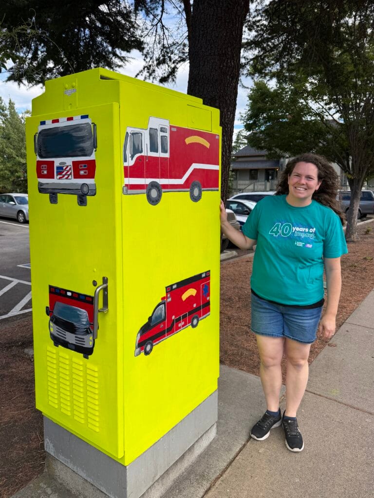 Artist Glory Nylander with the completed traffic signal box she designed: "Fire Engine and Ambulance."